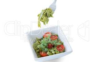 Pasta salad in bowl with fork on white background
