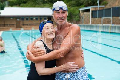 Senior couple embracing each other at poolside