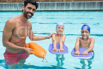 Smiling coach assisting a kids in swimming in pool