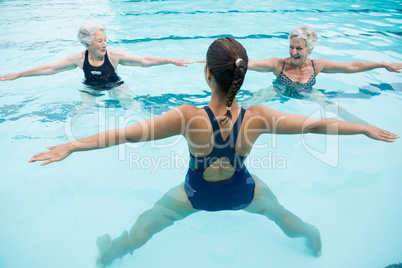 Female trainer with senior women exercising in swimming pool