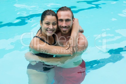 Smiling couple embracing in swimming pool