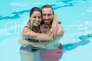 Smiling couple embracing in swimming pool