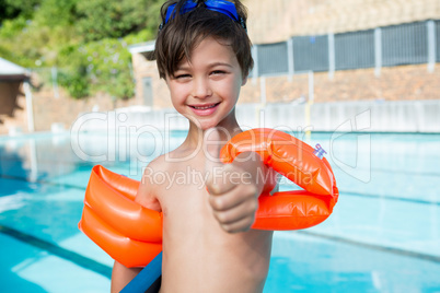 Young boy showing thumbs up at poolside