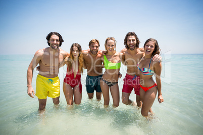 Cheerful couples in beachwear standing in sea