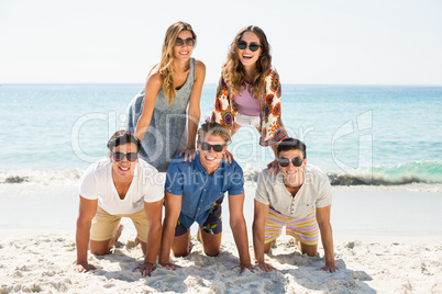 Young friends forming pyramid at beach