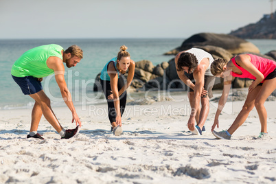Young friends exercising on shore at beach