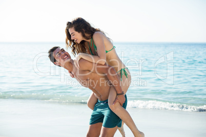 Boyfriend piggybacking girlfriend on shore