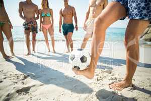 Man balancing soccer ball against friends