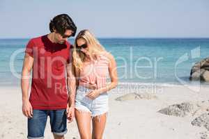 Couple wearing sunglasses while standing at beach