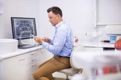 Portrait of happy dentist using mobile phone