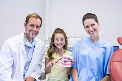 Dentists and young patient holding model teeth in dental clinic