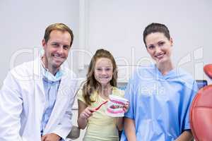 Dentists and young patient holding model teeth in dental clinic