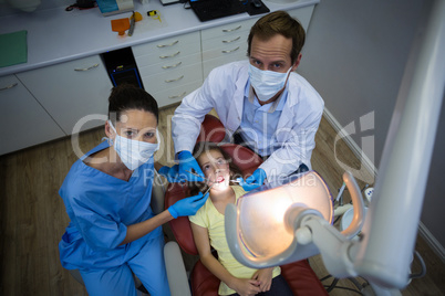 Dentists examining a young patient with tools in dental clinic