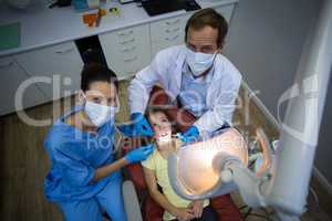 Dentists examining a young patient with tools in dental clinic