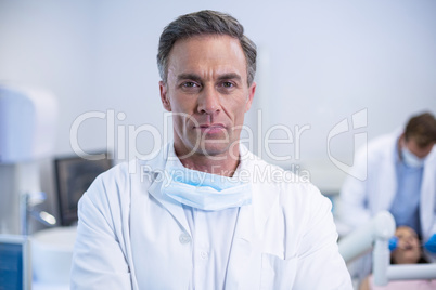 Confident dentist standing at dental clinic