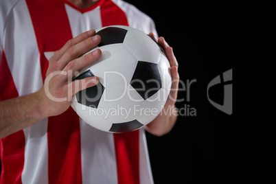Mid-section of football player holding football with both hands