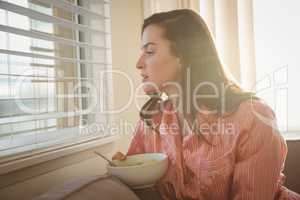 Woman looking through window while sitting on sofa