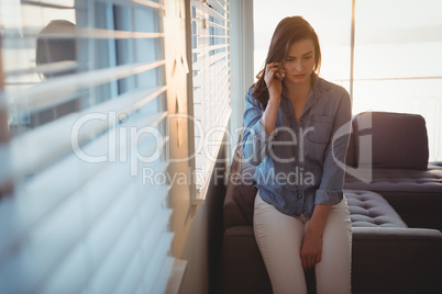 Woman talking on smart phone while sitting on sofa