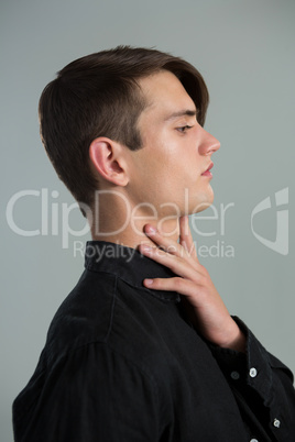 Androgynous man touching his neck