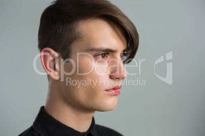 Androgynous man looking sideways against grey background