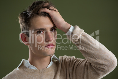 Androgynous man touching his hair against green background