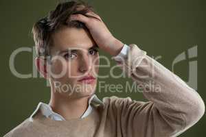 Androgynous man touching his hair against green background