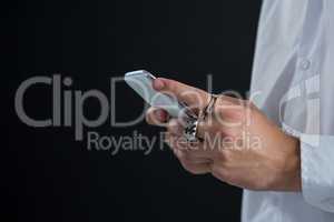 Androgynous man using mobile phone against black background