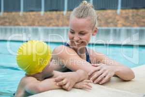 Female instructor and young boy relaxing at poolside