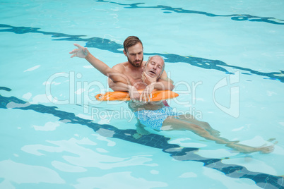 Lifeguard rescuing senior man from swimming pool