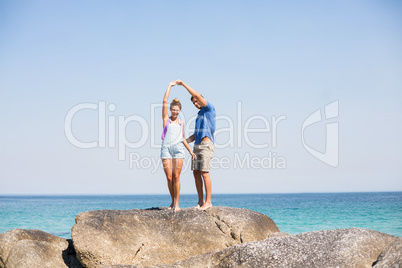 Young couple dancing on rock by sea