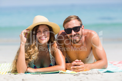 Happy couple lying at beach during sunny day