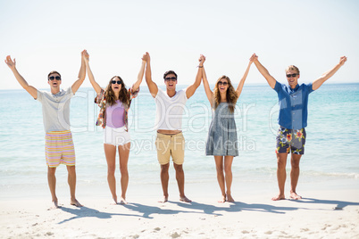 Happy friends with arms raised at beach