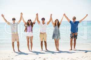 Happy friends with arms raised at beach