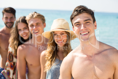 Happy young friends standing against sea