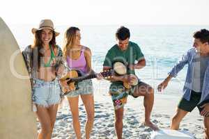 Friends enjoying music while standing at beach
