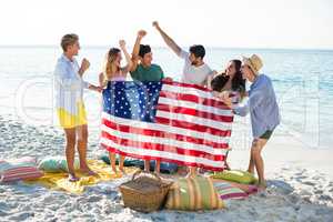 Friends holding American flag on shore at beach