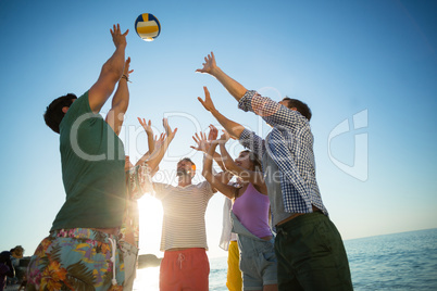 Low angle view of friends playing volleyball on shore