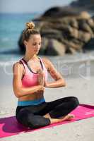 Beautiful woman meditating while sitting at beach
