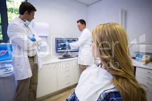 Dentist discussing teeth x-ray with his colleague and patient