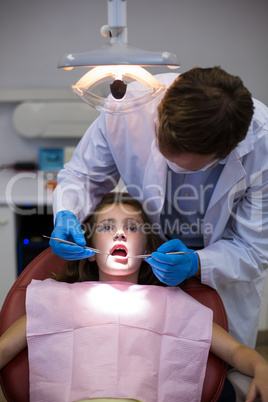 Dentist examining a young patient with tools