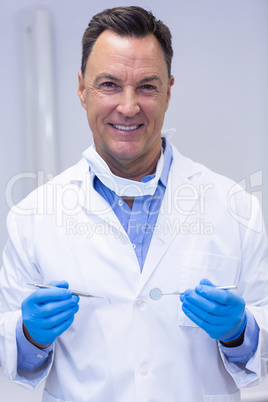 Portrait of smiling dentist holding dental tools