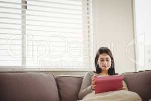 Woman using tablet while sitting on sofa