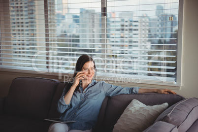 Woman talking on mobile while sitting on sofa