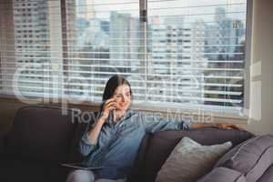 Woman talking on mobile while sitting on sofa