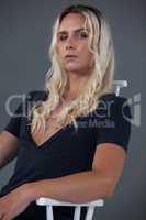 Transgender woman sitting on chair over gray background