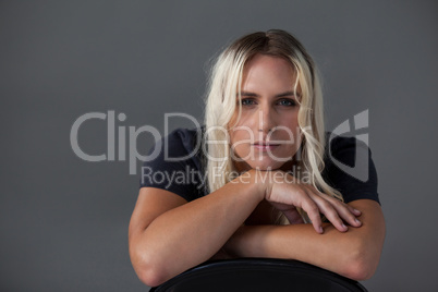 Beautiful transgender woman leaning on chair over gray background