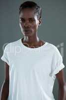 Androgynous man in white top posing against grey background