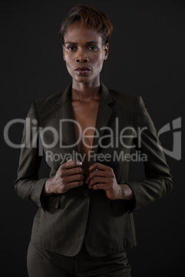 Androgynous man in suit posing against grey background