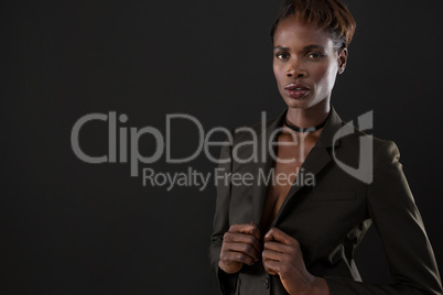 Androgynous man in suit posing against grey background