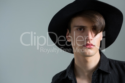 Androgynous man in hat posing against grey background